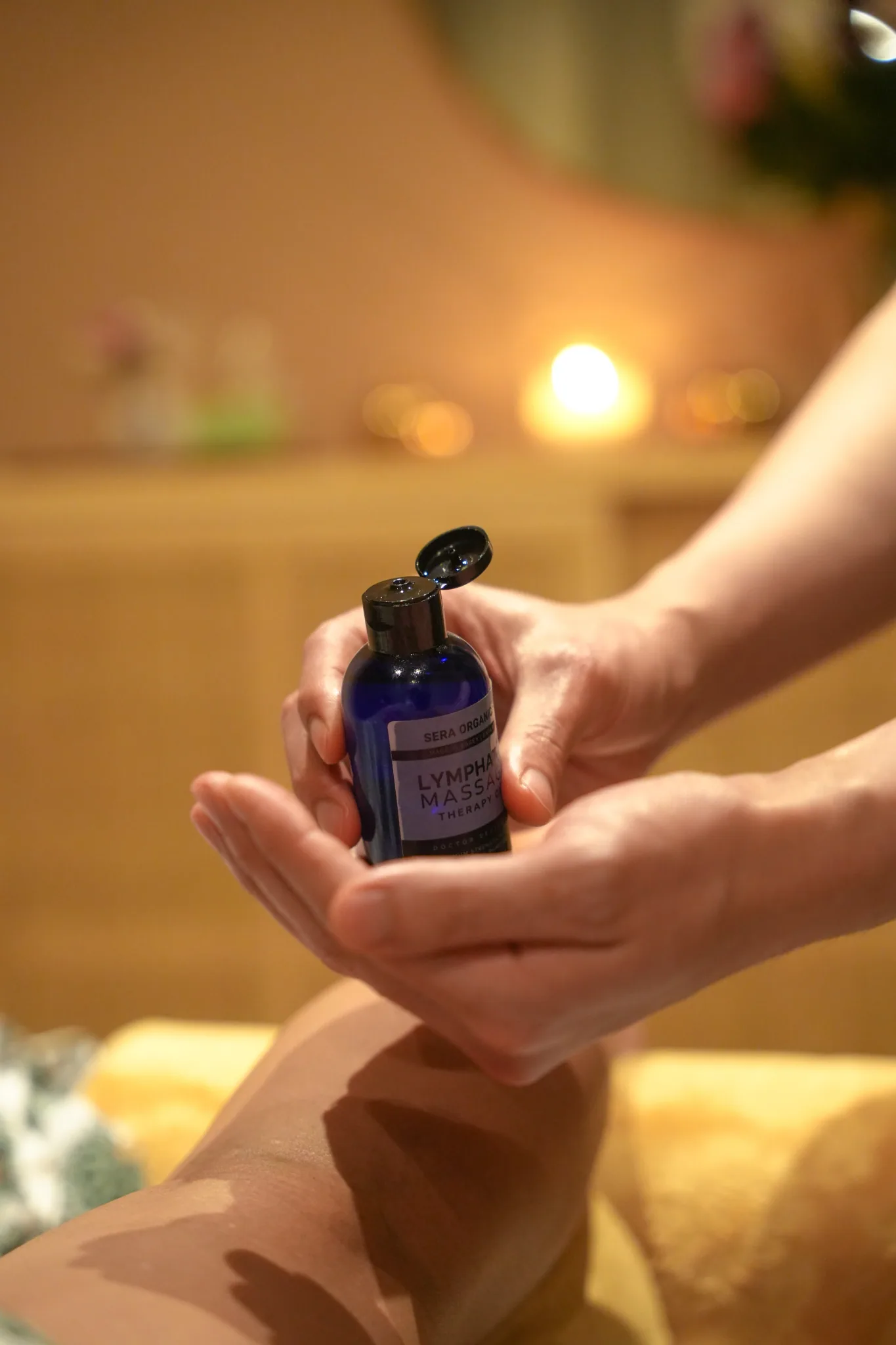 Massage oil being poured from a bottle into a therapist's hand